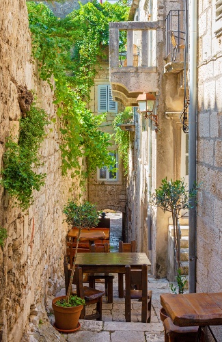 Tiny street in Korcula Old Town with table and plants