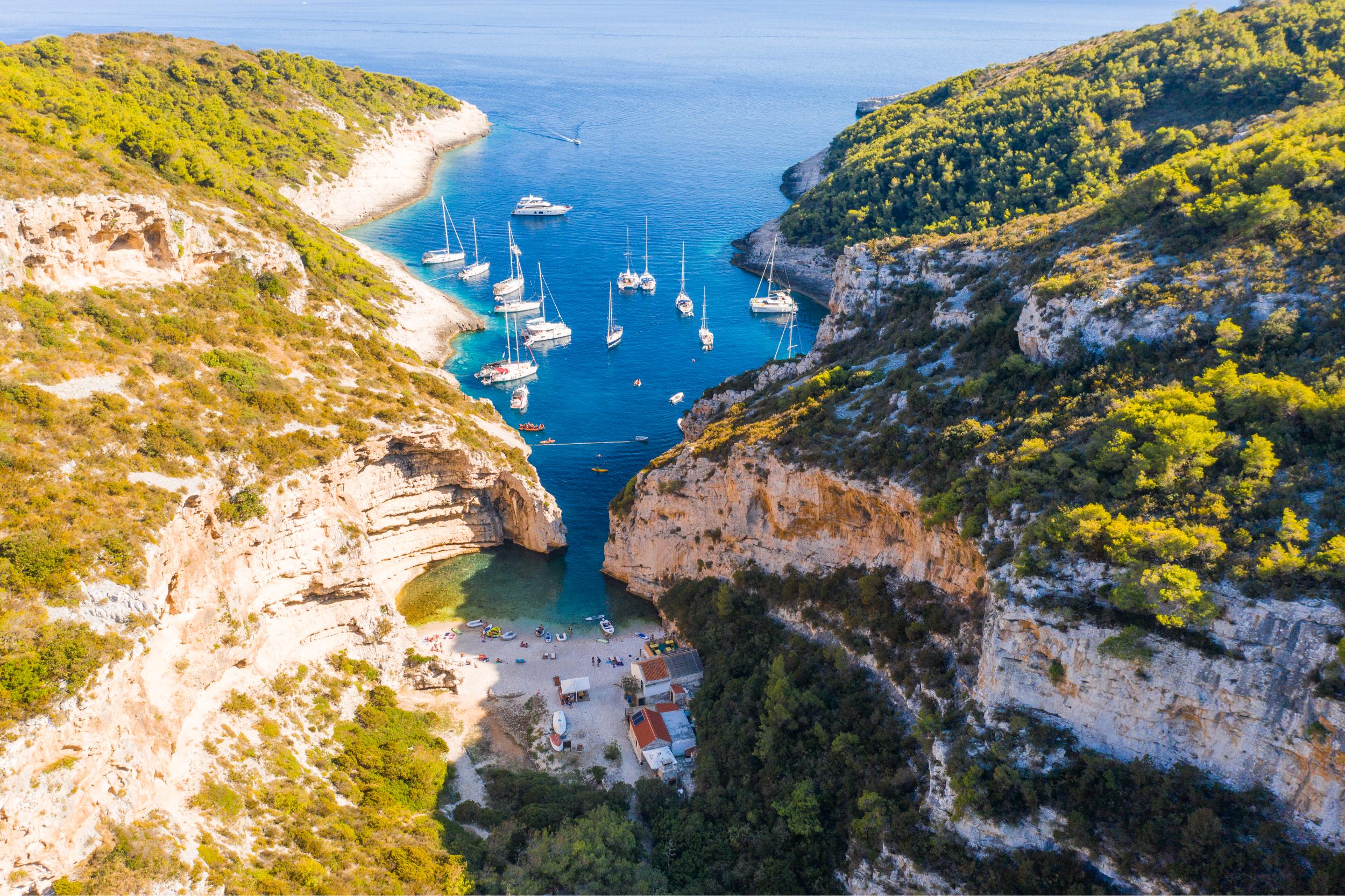Famous beach in Vis Stiniva Cove with sailing boats