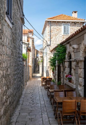 A view of a street with restaurant tables in the old town of Vis